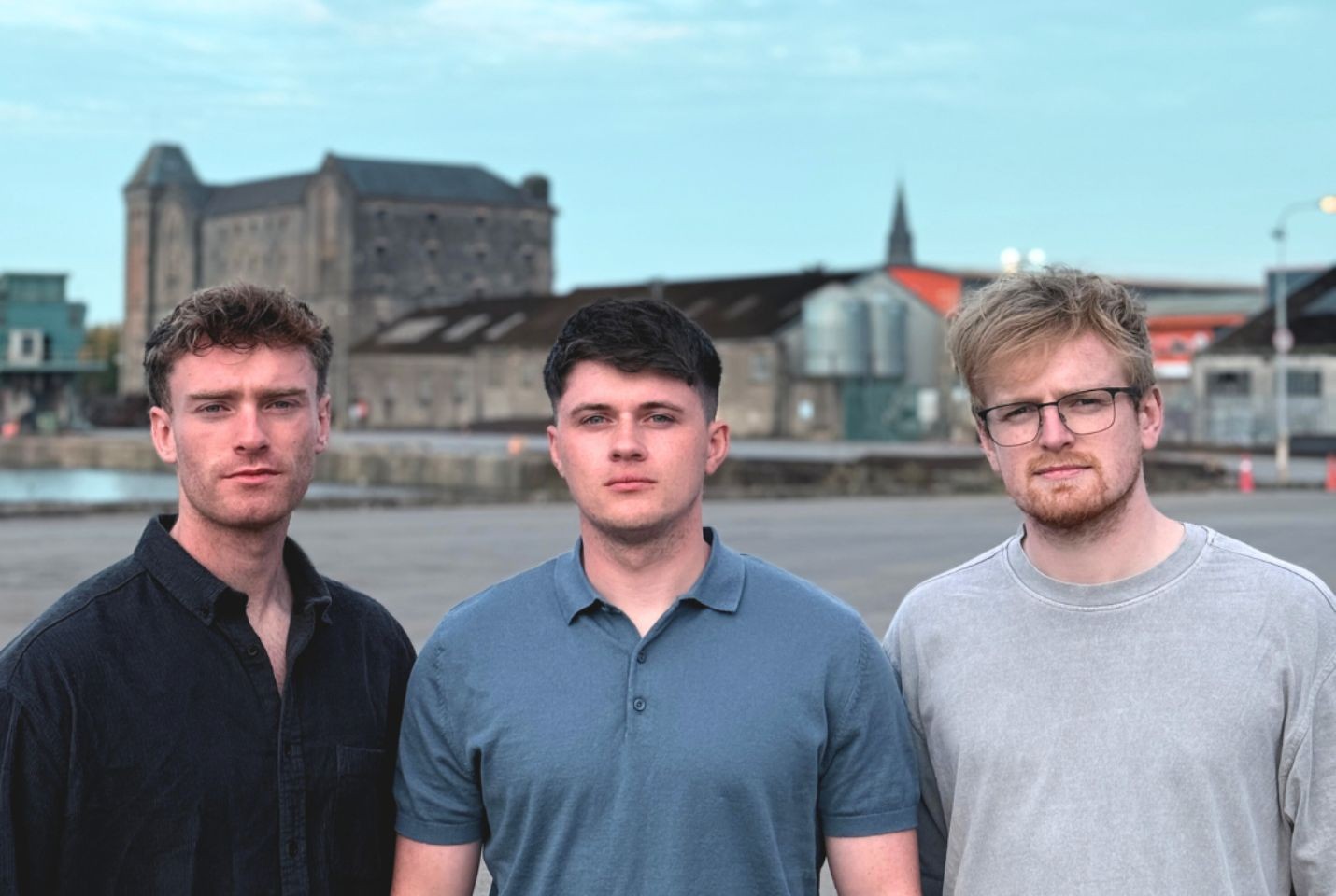 Three men stood against village background